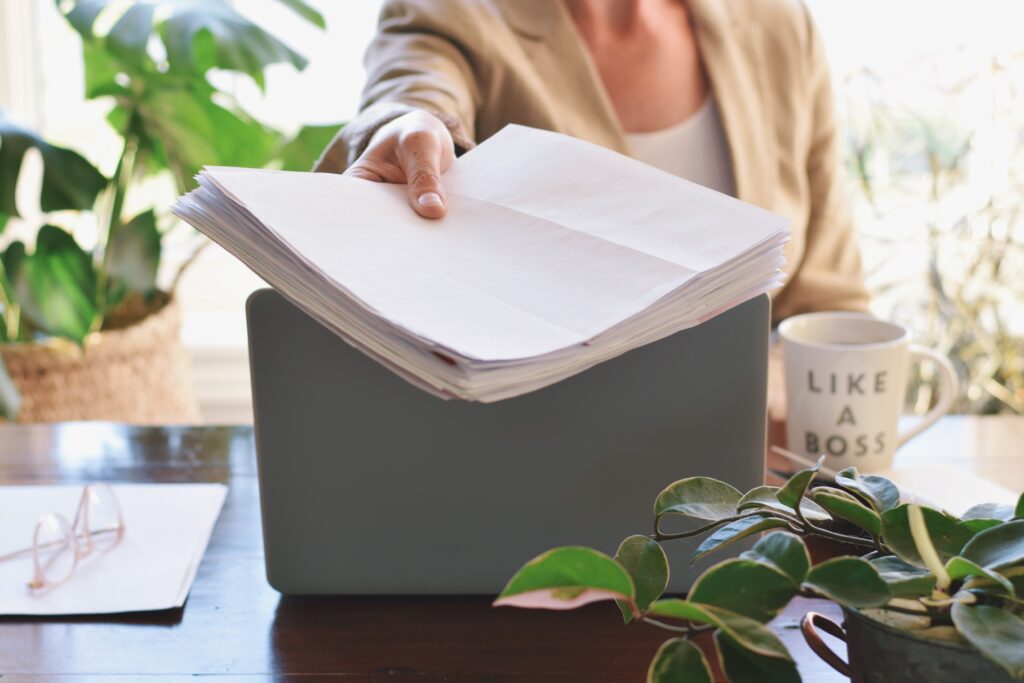 Woman is sitting at a desk holding giving business development paperwork to someone